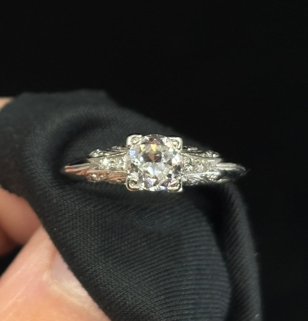 Close-up of a 1920s Art Deco platinum ring with a 0.46ct semi‑modern cut diamond and carved pavé shoulders.
