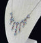 Close-up detail of moonstones and rubies on a 1920s sterling silver necklace, highlighting the intricate claw setting.
