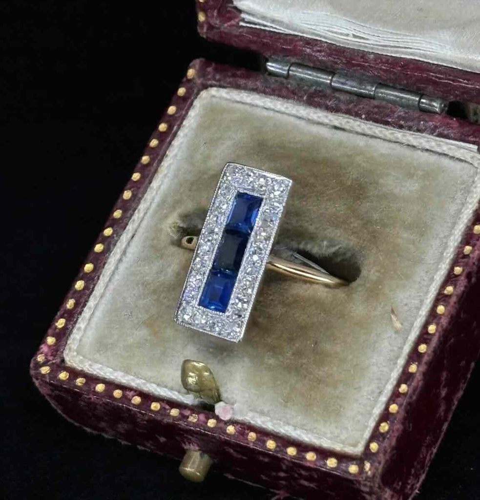 Close-up of an Art Deco ring with sapphire and diamond rectangular cluster design.