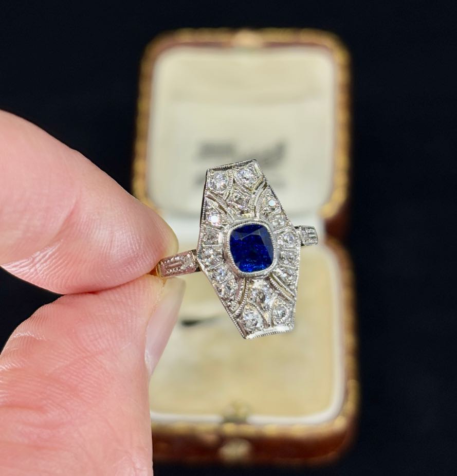 Antique Art Deco sapphire and diamond tonneau-shaped cluster ring from the 1930s with a royal blue cushion cut sapphire.