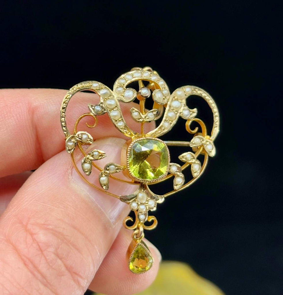 Close detail of antique green garnet and pearl set gold brooch showing early 20th century craftsmanship.