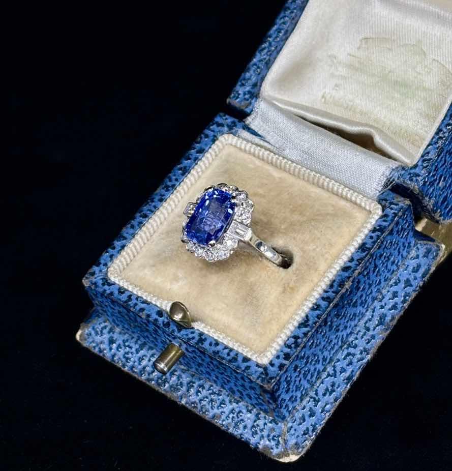 Stunning blue Ceylon sapphire cluster ring featuring a cushion-shaped diamond border in white gold.