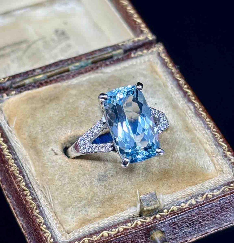 Cushion mixed cut aquamarine ring highlighted by diamonds.