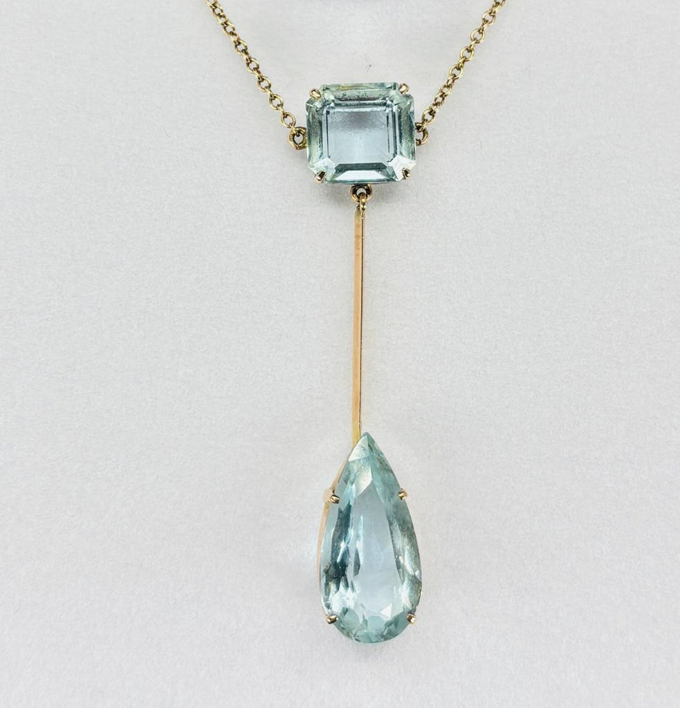 Close up of Edwardian aquamarine pendant showing emerald cut and pear cut aquamarines set in 9ct yellow gold
