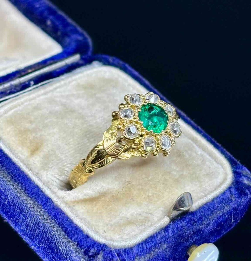 Close-up of fine green emerald and diamond cluster in Victorian gold ring.