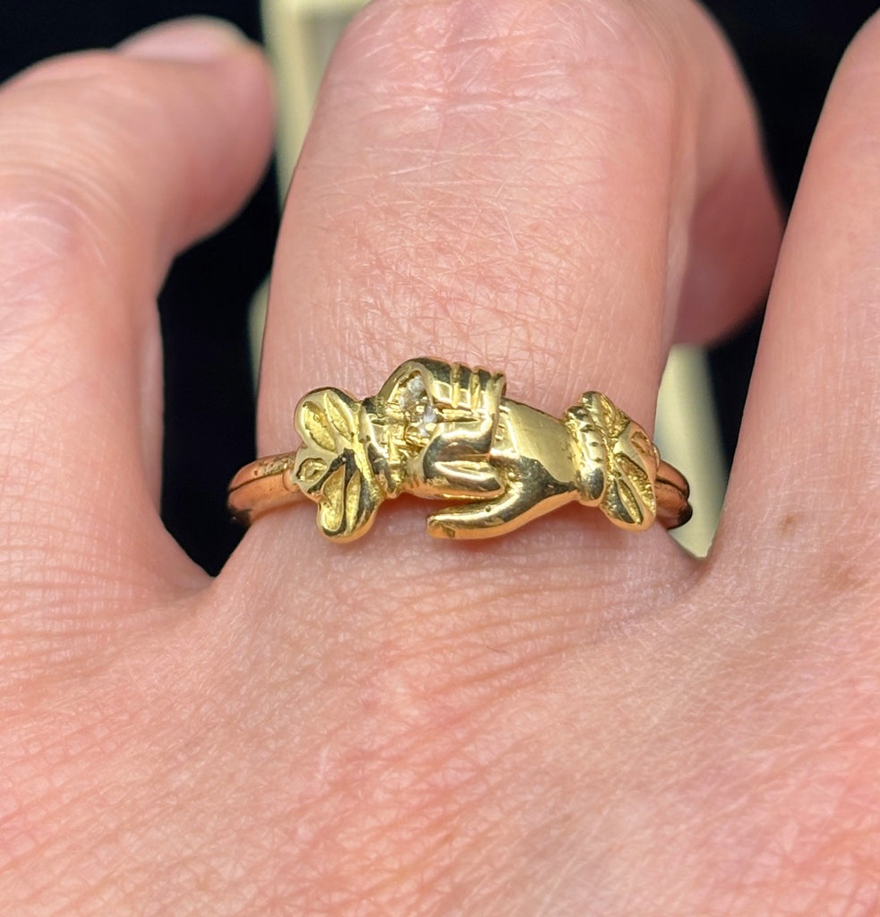 Georgian gold fede ring worn on finger showcasing clasped hands.