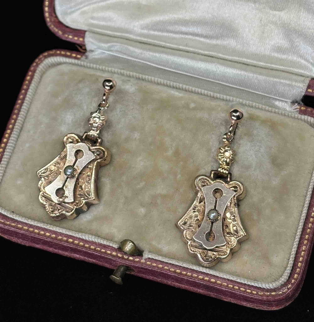 Detail view of Victorian 9ct rose gold articulated drop earrings with engraved escutcheon-style panels and natural seed pearls.