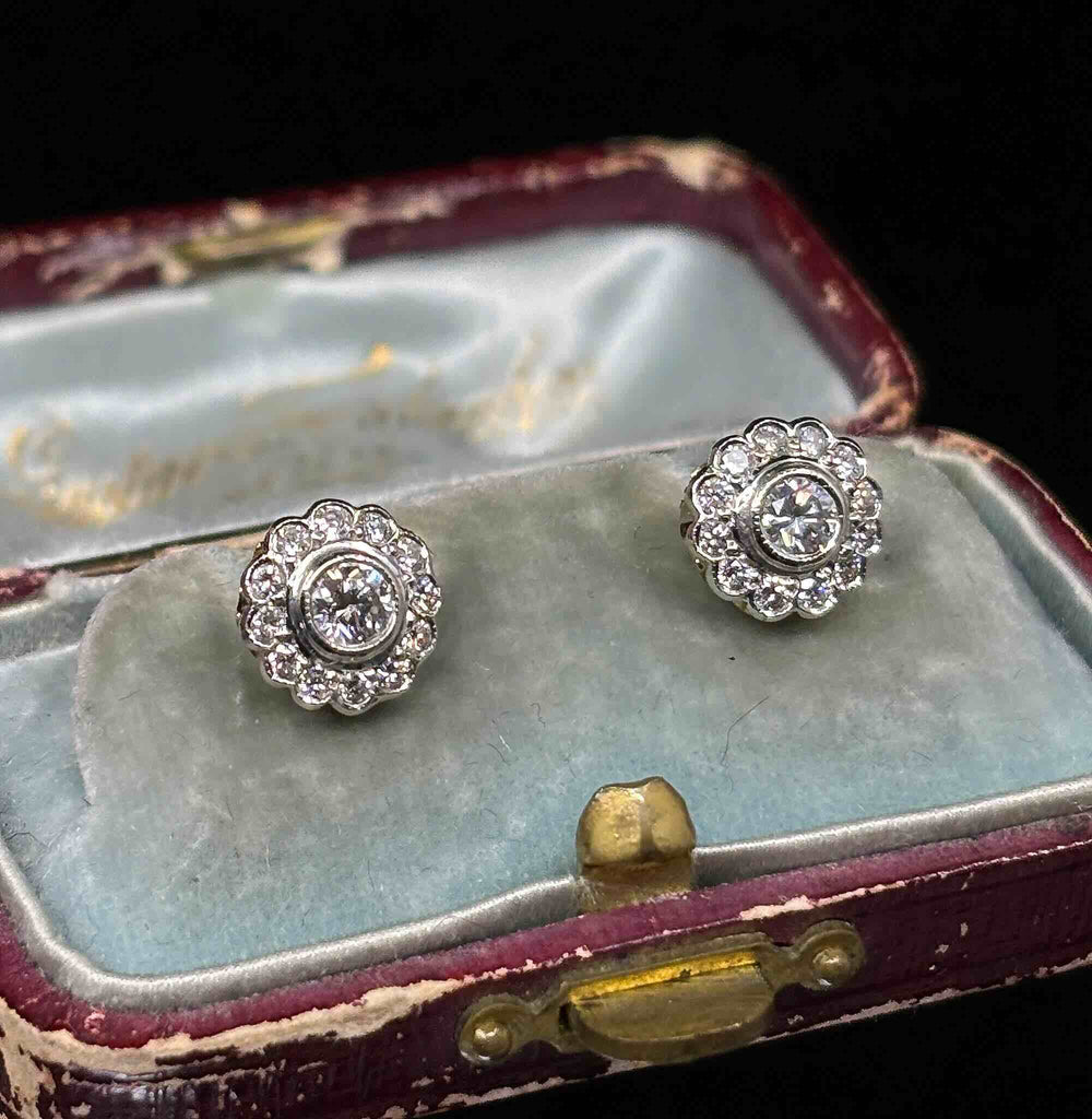 Angled view of diamond posy cluster stud earrings in 18ct white and yellow gold, shown in their fitted presentation case.