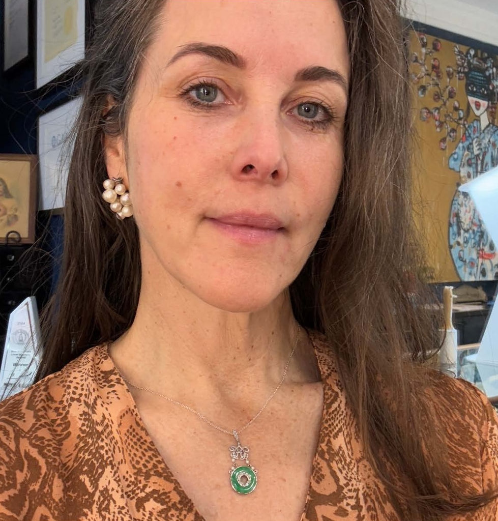 Jade pi pendant showcasing vivid green jadeite disc framed by 45 rose‑cut diamonds and four natural pearls worn on the neck