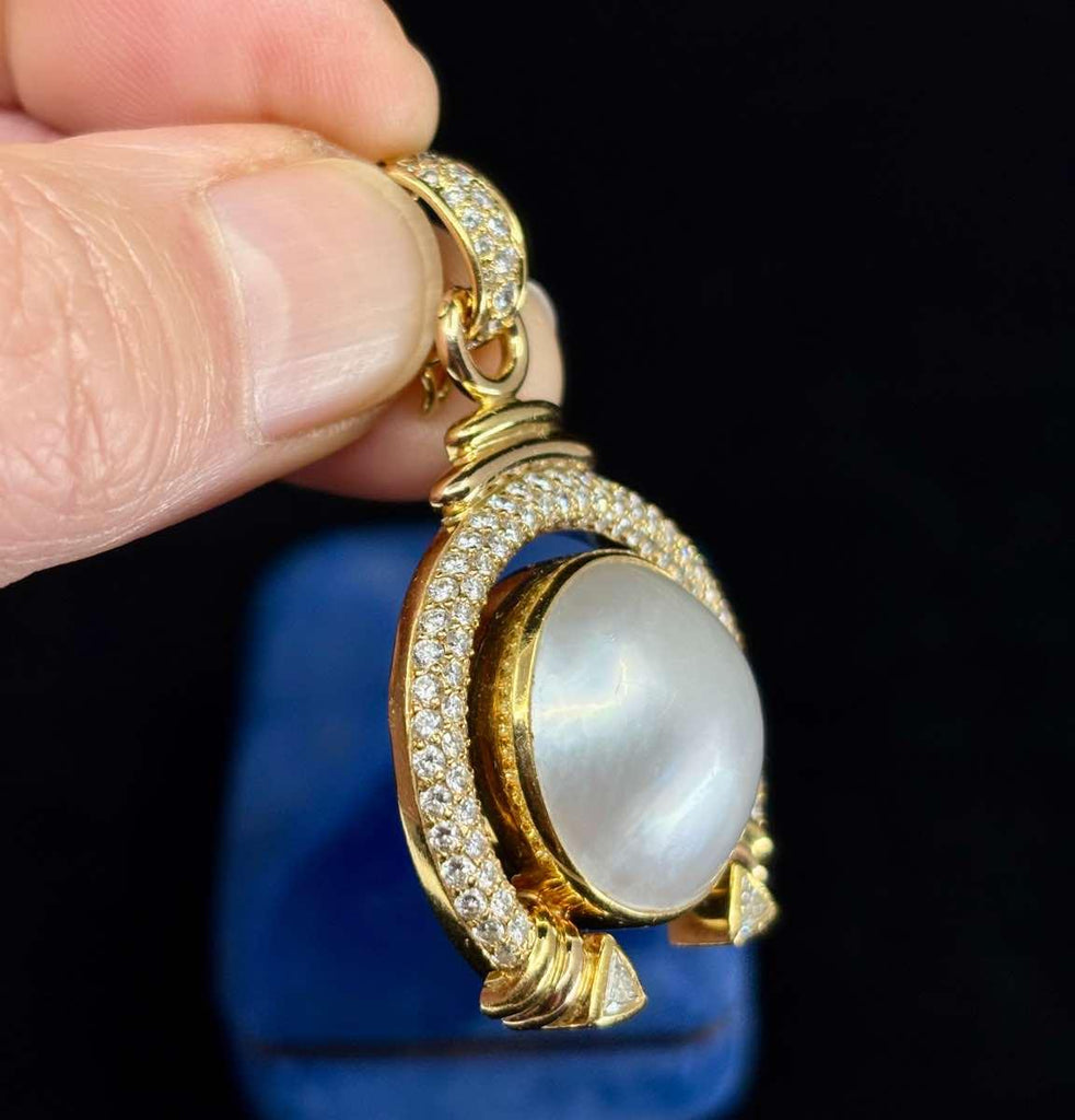 Luxury jewelry featuring a Mabé pearl surrounded by diamonds in a yellow gold setting.