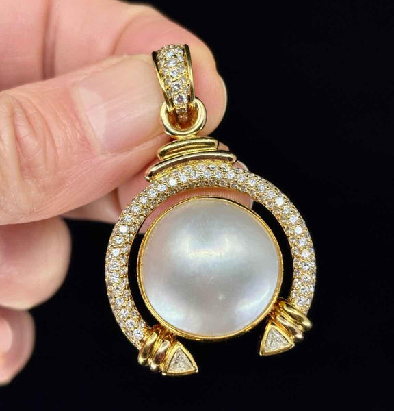 Front view of an 18ct yellow gold Mabé pearl and diamond pendant with intricate scrollwork.