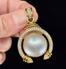 Front view of an 18ct yellow gold Mabé pearl and diamond pendant with intricate scrollwork.