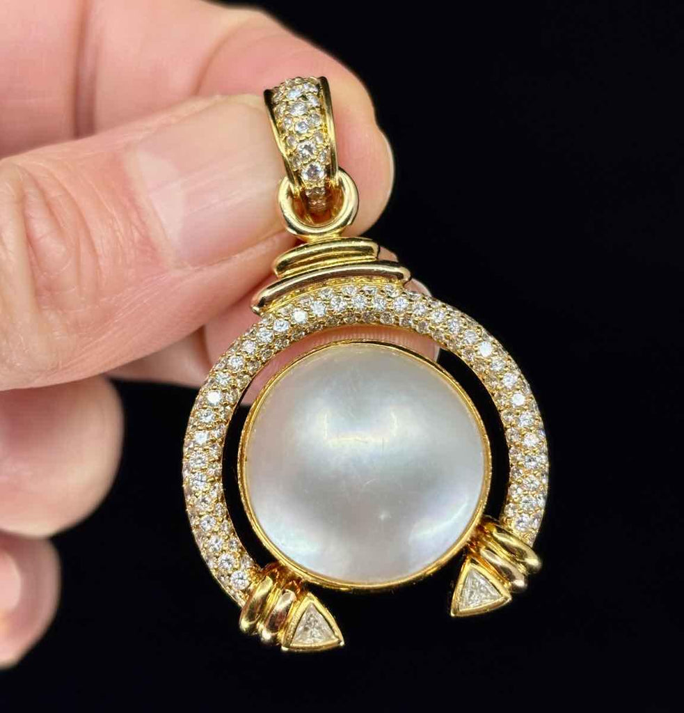 Front view of an 18ct yellow gold Mabé pearl and diamond pendant with intricate scrollwork.