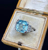 Mid-century cocktail ring featuring a large emerald-cut aquamarine and subtle single-cut diamonds — elegant vintage 1950s design.