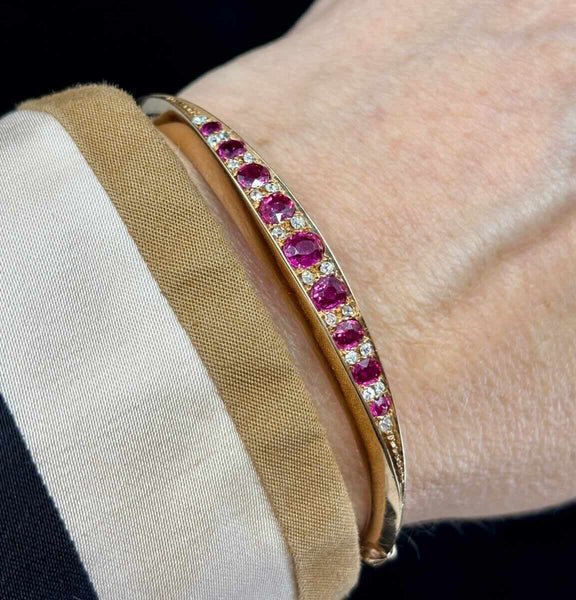 Victorian 1895 hinged bangle in 15ct yellow gold set with nine oval natural rubies (1.65ct) and 18 old‑cut diamonds worn on the wrist.