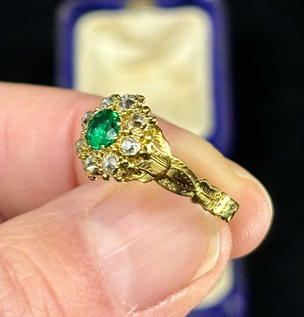 Detailed view of Victorian emerald ring with fine green gemstone and diamond cluster.
