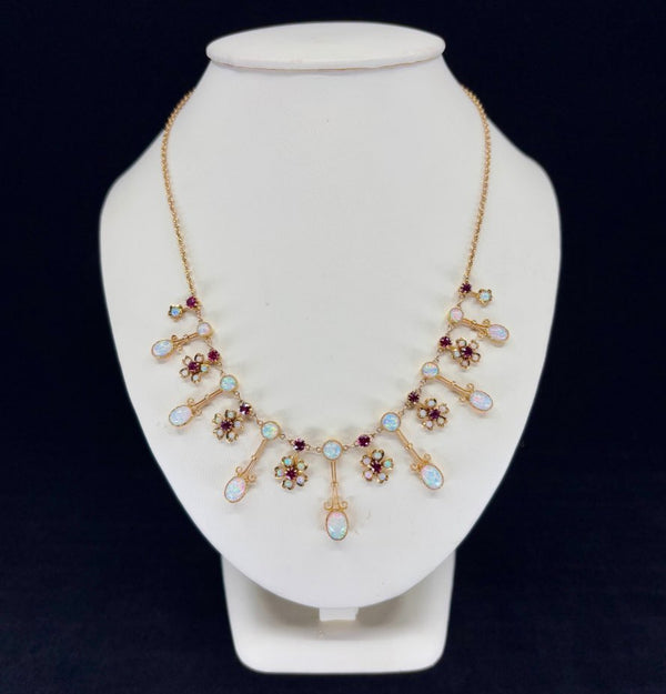 Front view of an antique Victorian opal and ruby fringe necklace in 15ct yellow gold, featuring 16 solid white crystal opals and 14 round rubies, circa 1895.