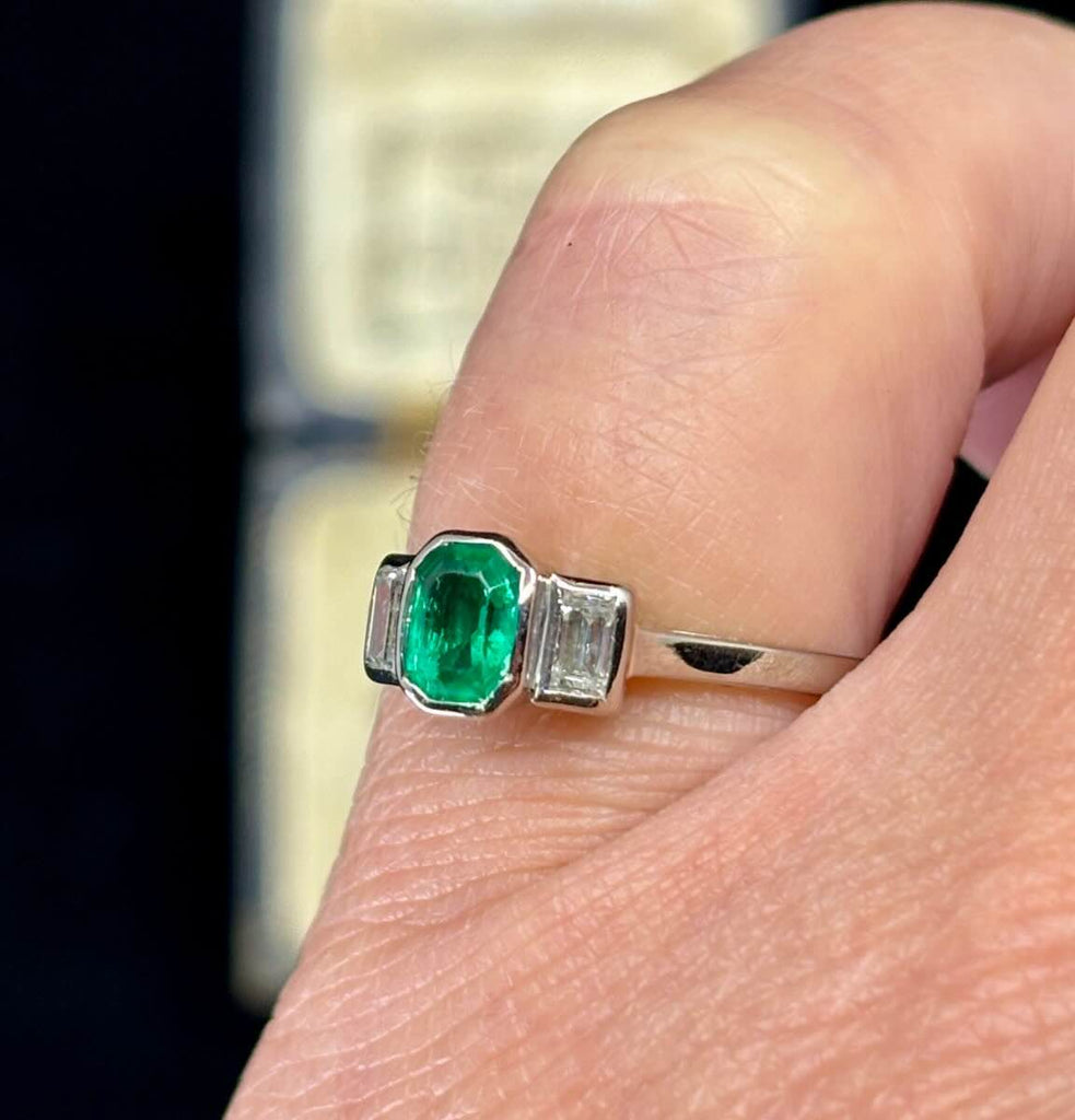 A side view on the finger or the 1940s vintage emerald and diamond ring