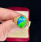 A hand wearing a classic 1940s black opal ring, highlighting the opal's vibrant colors and gold craftsmanship.