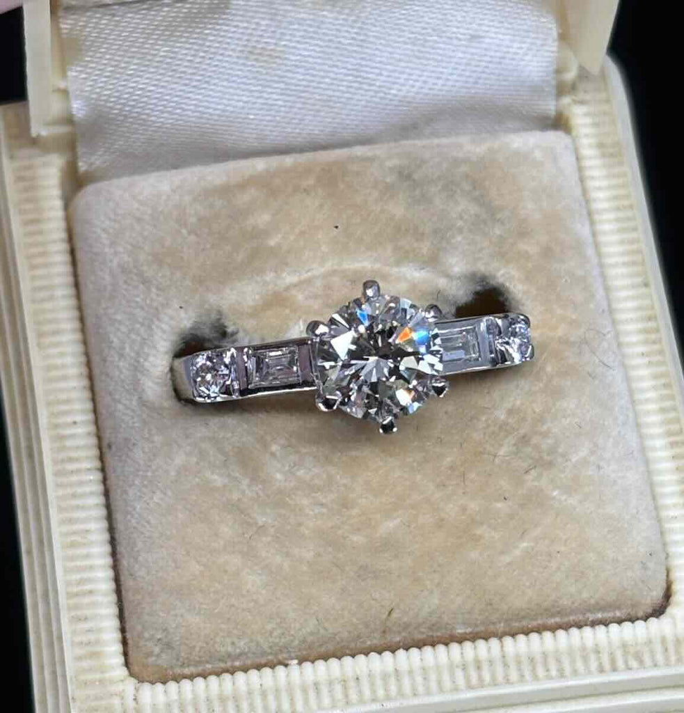 Close-up of vintage 1950s round brilliant 1.30ct diamond set in six-claw 18ct white gold with baguette and round shoulder stones.