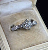 Detail of tapered band and baguette shoulder diamonds on a 1950s brilliant cut engagement ring, 18ct white gold craftsmanship and vintage styling.