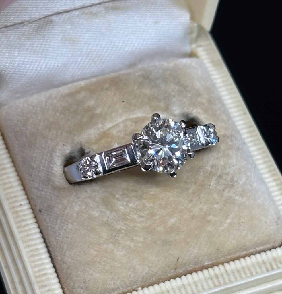 Detail of tapered band and baguette shoulder diamonds on a 1950s brilliant cut engagement ring, 18ct white gold craftsmanship and vintage styling.