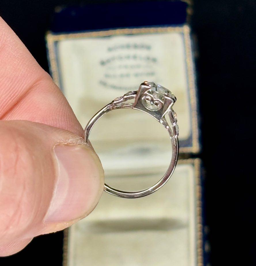 Close-up of a vintage Art Deco engagement ring detailing the brilliant cut diamond and intricate platinum setting from the 1920s.