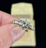 Vintage 1950s brilliant cut diamond engagement ring in 18ct white gold, 1.30ct center stone with baguette shoulder diamonds, top view in antique ring box.
