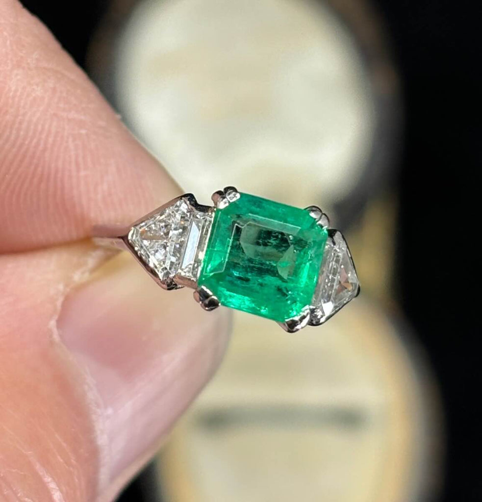 Vintage Art Deco emerald-cut emerald ring, medium green 1.25ct stone flanked by shield and baguette diamonds.