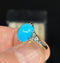  Detailed view of an Art Deco vintage ring featuring an oval turquoise center piece surrounded by sparkling diamond accents on the shoulders.