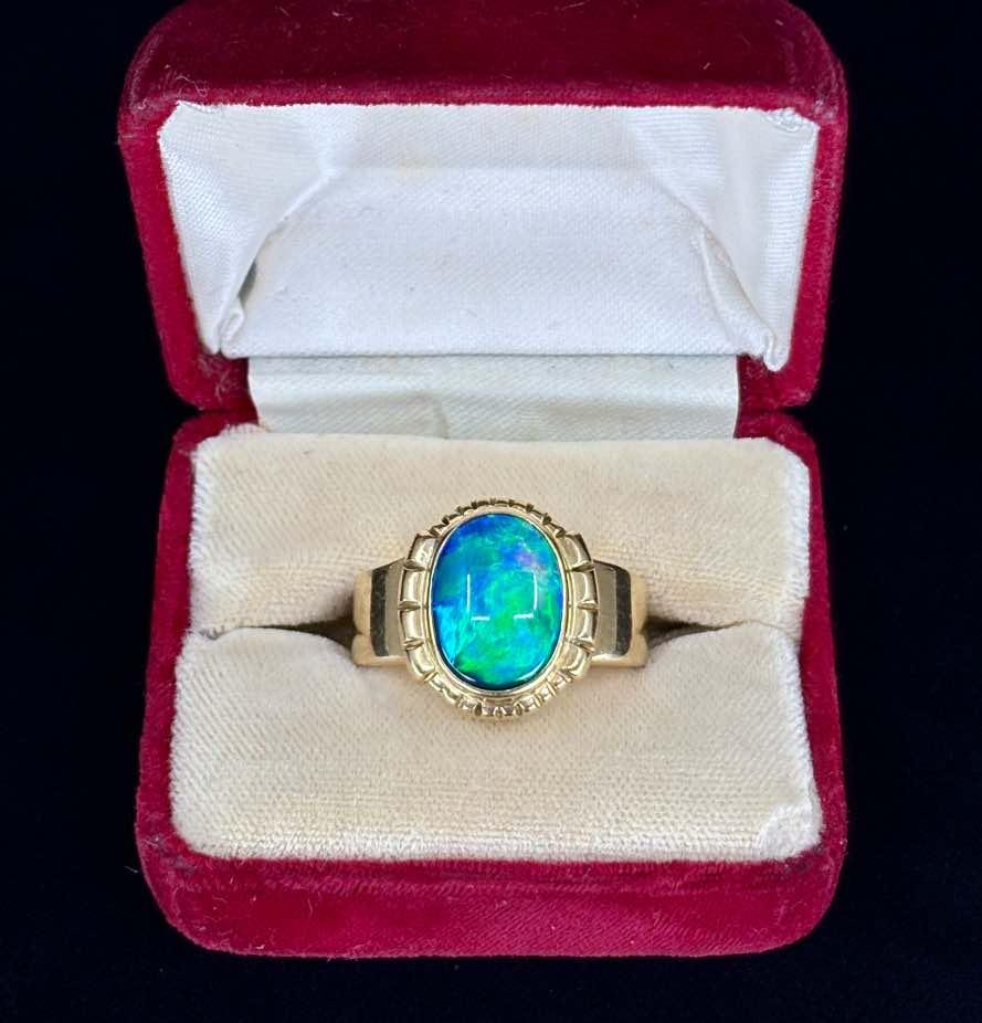 Close-up of a vintage 1940s ring featuring a vibrant oval black opal set in 18ct yellow gold."