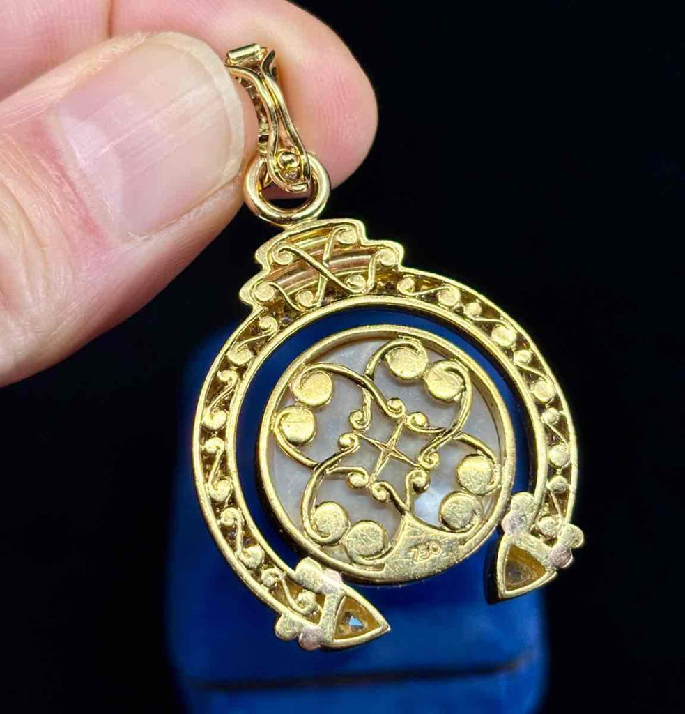 Close-up of hand saw-pierced scrollwork on the back of a gold pendant.